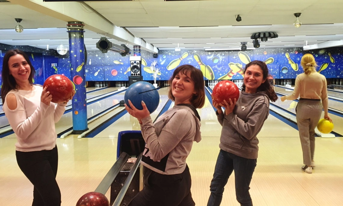 [Translate to English:] Studentinnen zeigen ihre Bowling-Kugel beim Treffen mit den Erstsemesterstudentinnen beim Bowling