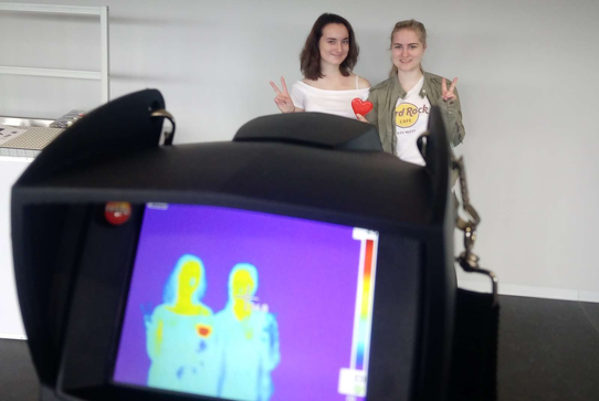 Vorne das Bild einer Wärmebildkamera, im Hintergrund die beiden fotografierten Mädchen