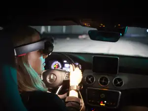 Frau mit VR-Brille in Auto in der Testhalle