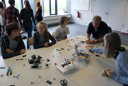 Mehrere Schülerinnen sitzen am Tisch und bauen das Boot aus PET-Flaschen