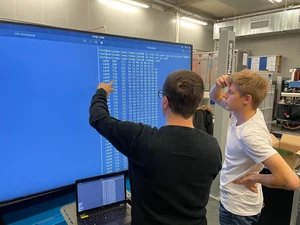 Zwei Personen vor Großbildschirm mit Testdaten