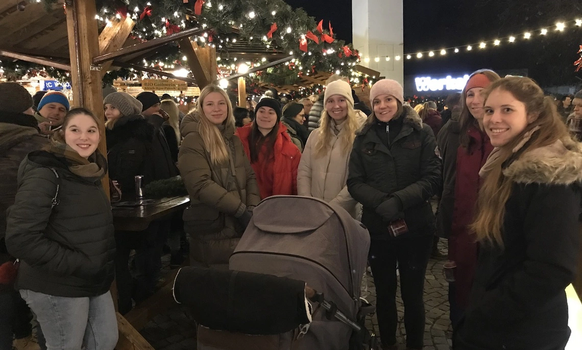 Mentoring-Teilnehmerinnen stehen in einer Gruppe an einem Stand am Ingolstädter Christkindlmarkt