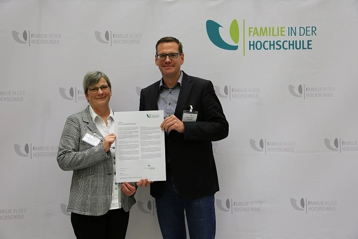 THI-Kanzler Christian Müller bekommt von einer Mitarbeiterin des Familienministeriums das Zertifikat „familiengerechte Hochschule“ überreicht