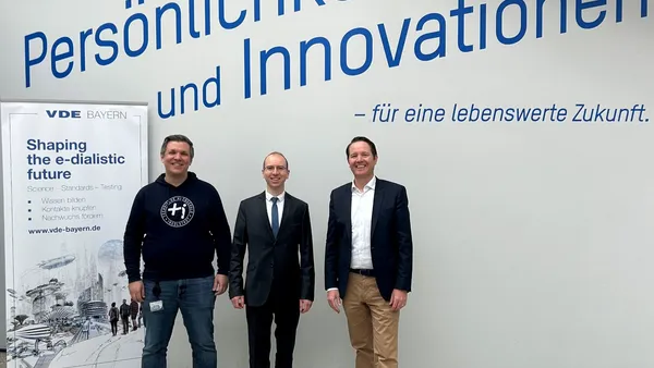 Bild von drei Männern in der Aula der THI mit einem Banner von VDE Bayern im Hintergrund