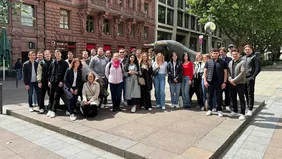 eine Gruppe Menschen positioniert um den Stier und Bär vor der Deutschen Börse.