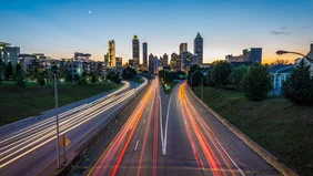 : A multi-lane road crisscrossed with colorful lines in the foreground, the skyline of a city in the background
