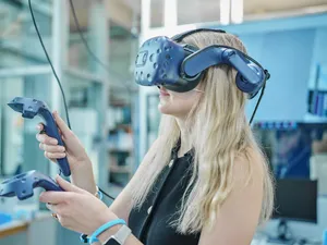 Eine Frau trägt eine VR-Brille und hält zwei Controller in den Händen
