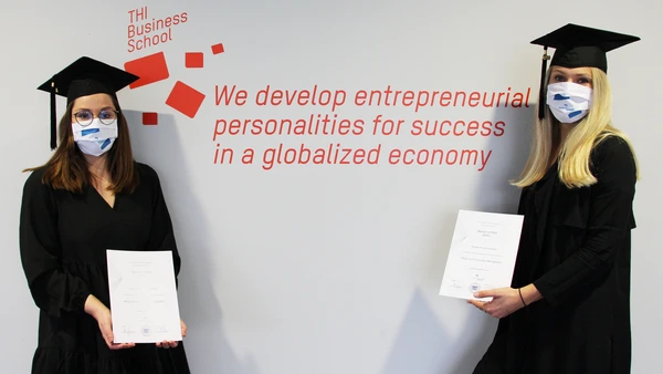 Two garduates holding the certificates in their hands