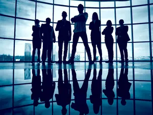 Business-Team steht vor einem Fenster mit Führungsperson im Vordergrund