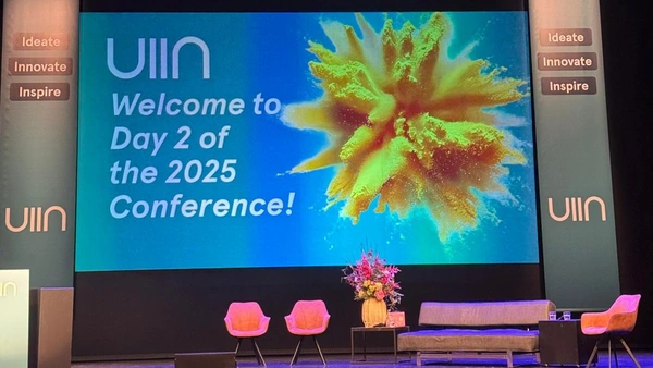 Foto der Bühne mit der Präsentation im Hintergrund auf der steht: UIIN Welcome to Day 2 of the 2025 Conference!