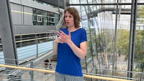 A woman using sign language in a modern glas building.