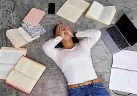 Frau liegt auf Rücken, rundum von Büchern umgeben