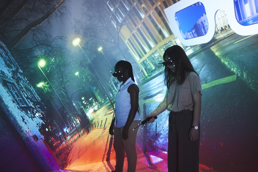 Zwei Frauen in der CAVE im VR-Lab, Hintergrund bunte Straßenszene bei Nacht