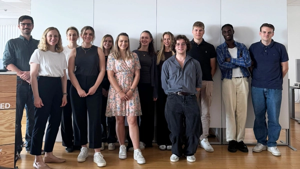 A group photo of 12 people in front of a white wall. 