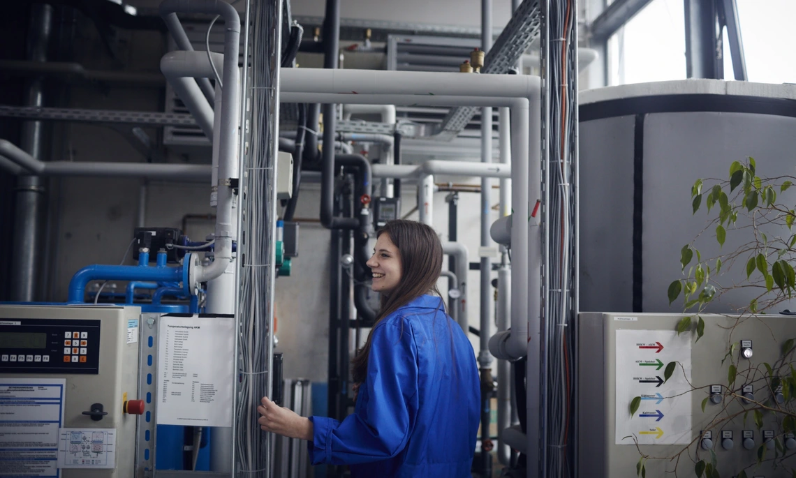 Mitarbeiterin steht vor der Wärme-Kälte-Pumpe im Labor
