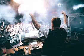 Bild von der 30 Jahr Feier mit einem DJ im Vordergrund und der Partygesellschaft im Hintergrund