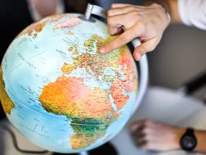 Ein Mitarbeiter des IO zeigt auf einen Globus