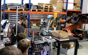 Professor zeigt SchülerInnen Roboter im Labor