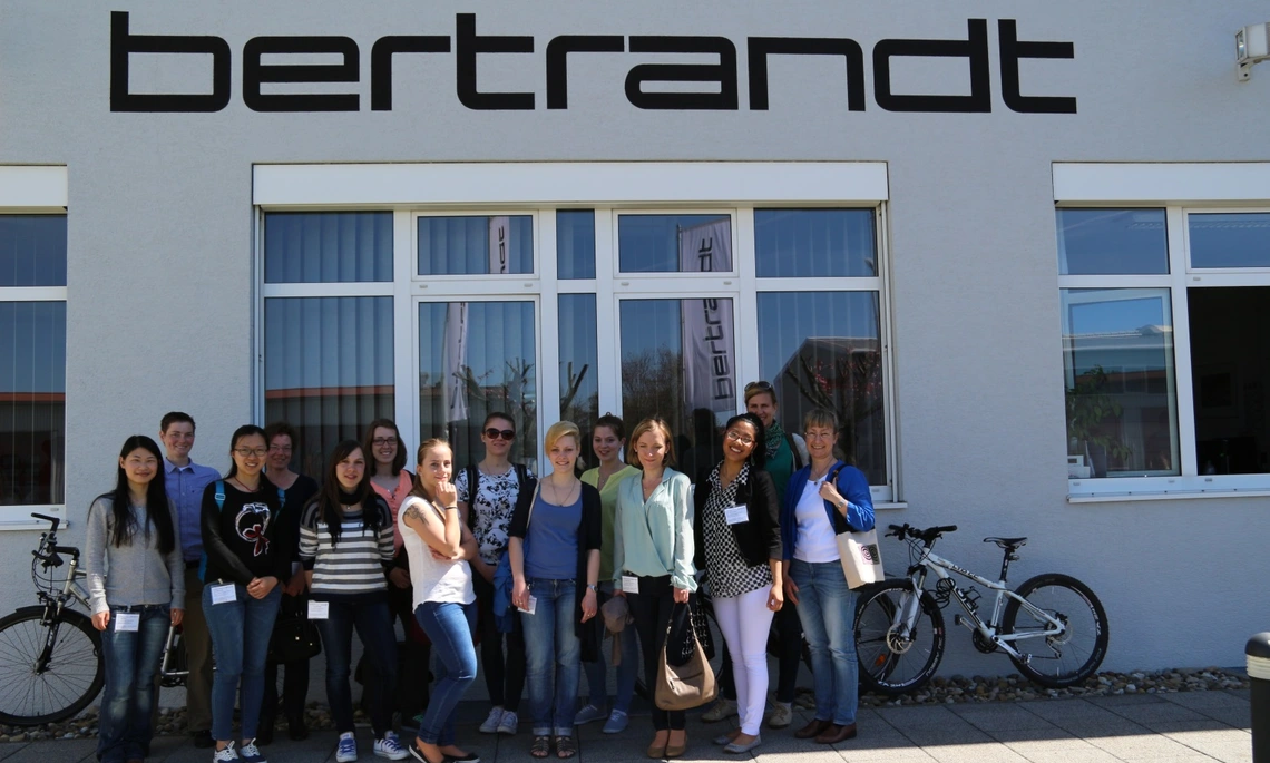 A group of female students stands in front of Bertrandt's company building