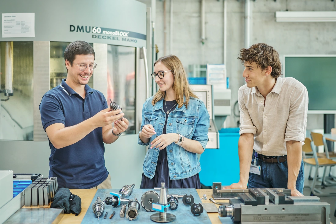 Zwei wissenschaftliche Mitarbeiter und eine wissenschaftliche Mitarbeiterin diskutieren im Labor wissenschaftliche Fragestellungen.