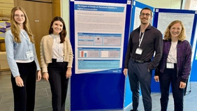 Four people in front of a pinboard. 