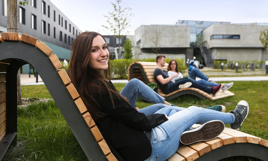 Studierende auf Holzliege auf Campuswiese
