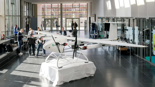 Einblick in das Urban Air Mobility Treffen in der Aula der THI, zusehen sind Ausstellungsmodelle sowie Gastgeber und Teilnehmer