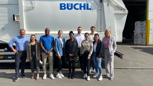 : A group of people in front of a disposal vehicle of the Büchl company. 