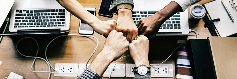 Five fists meet in the middle, laptops in the background