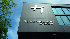 Haupteingang der Technischen Hochschule Ingolstadt mit Hochschullogo.