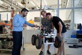 Bild aus dem Futurelab-Labir, wo Herr Kanso zwei Studierenden etwas anhand eines Roboters erklärt 
