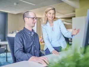 Eine weibliche und eine männliche Person schauen auf einen Bildschirm