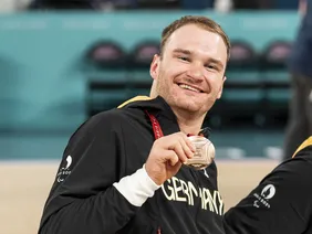 Portrait von Student Lukas Glossner bei einem sportlichen Wettbewerb, wie er seine Medaille zeigt