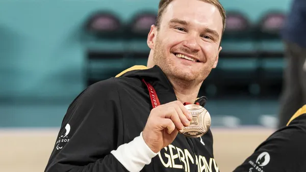 Portrait von Student Lukas Glossner bei einem sportlichen Wettbewerb, wie er seine Medaille zeigt