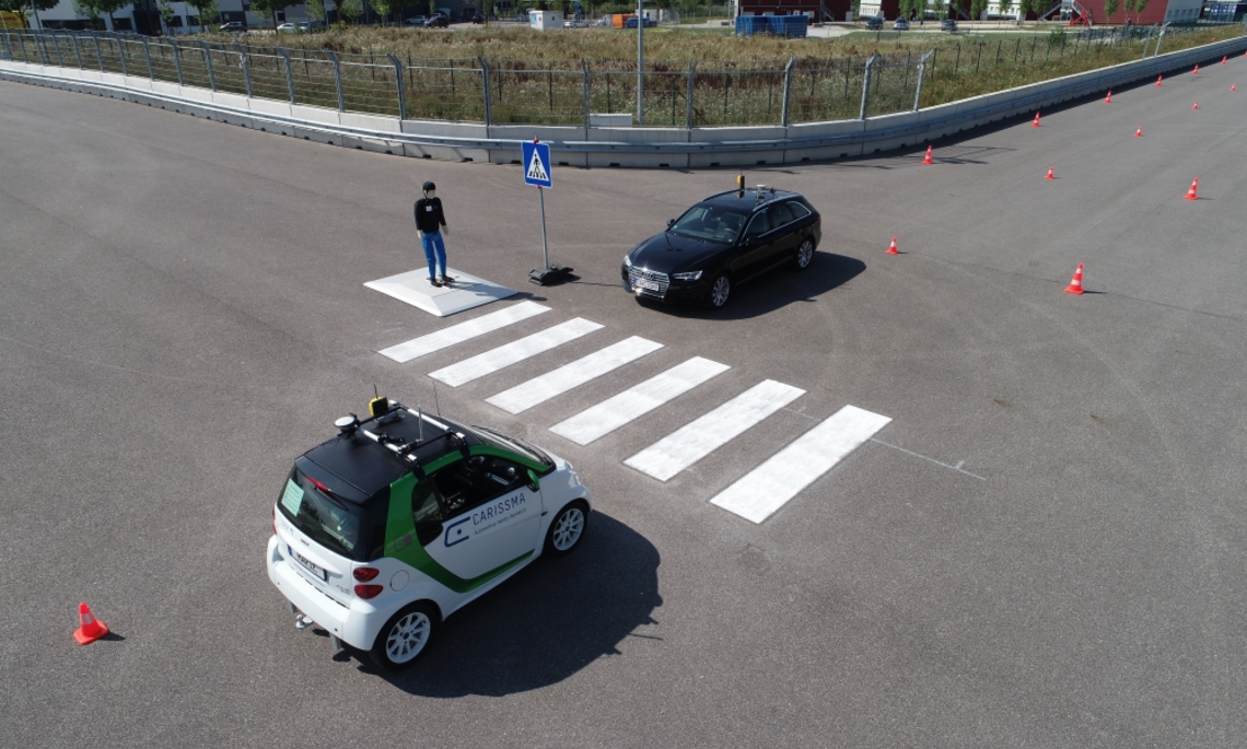 Illustration of a test scenario with two autonomously driving vehicles and a pedestrian dummy at a zebra crossing