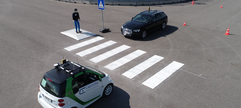 Abbildung zwei autonom fahrender Fahrzeuge an einem Zebrastreifen mit einem Fußgängerdummy