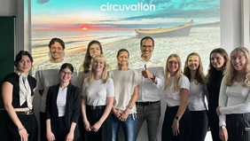 : A group of eleven people is smiling at the camera