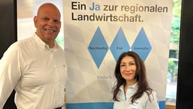 A man and a woman are standing in front of a billboard.