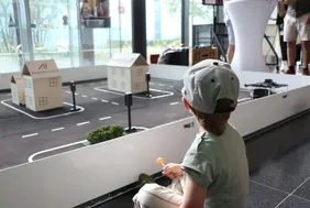 Kleines Kind sitzend auf dem Boden vor dem Modell des TurtleBot