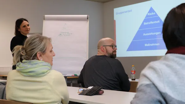 Bild aus einem Workshop, auf dem zwei Teilnehmende und die Leiterin des Workshops zu sehen sind