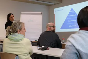 Bild aus einem Workshop, auf dem zwei Teilnehmende und die Leiterin des Workshops zu sehen sind