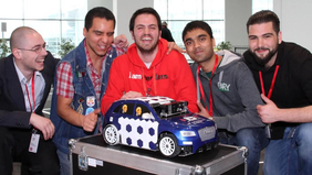 Five students in front of a model car at the "Audi Autonomous Driving Cup" competition