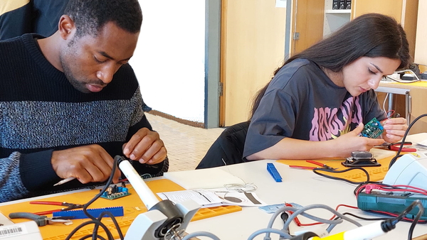 Students solder a robot together in the lecture hall