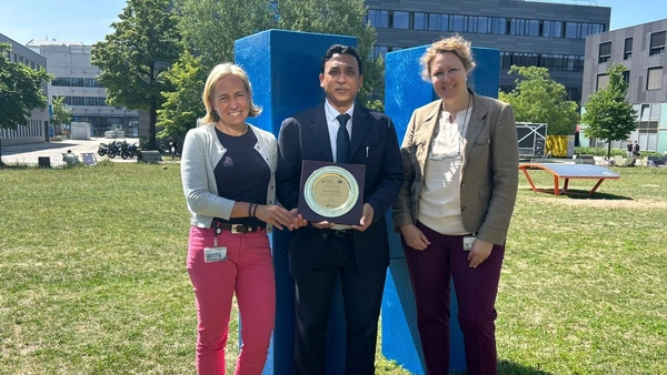 Three people are standing in a meadow and holding up a sign.  halten eine Plakette ins Bild 
