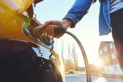 Person steckt Ladegerät in E-Auto.