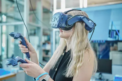 Eine Frau trägt eine VR-Brille und hält zwei Controller in den Händen