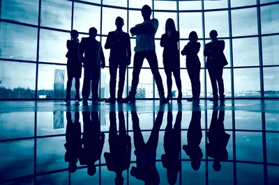 Business-Team steht vor einem Fenster mit Führungsperson im Vordergrund