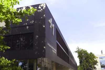 Campus Haupteingang mit Logo und Baum