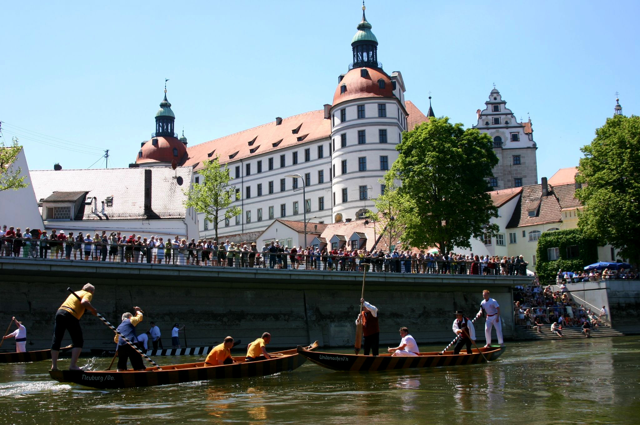 Neuburg Castle in the background, in front of it spectators at the fishing contest on the Danube
