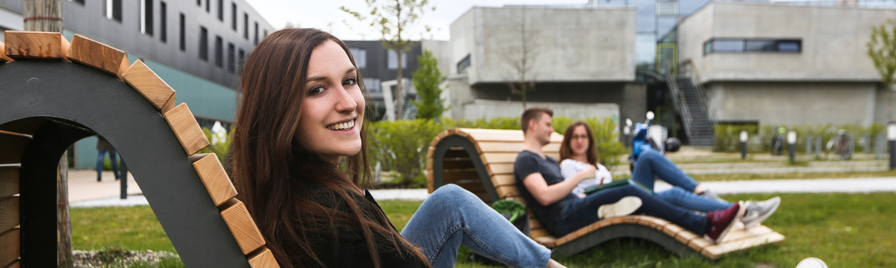 [Translate to English:] Banner Hochschulinfomrationstag - Studentin auf Campus-Wiese